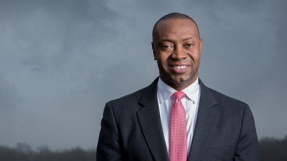 Marshall Shepherd smiling with storm clouds behind him.
